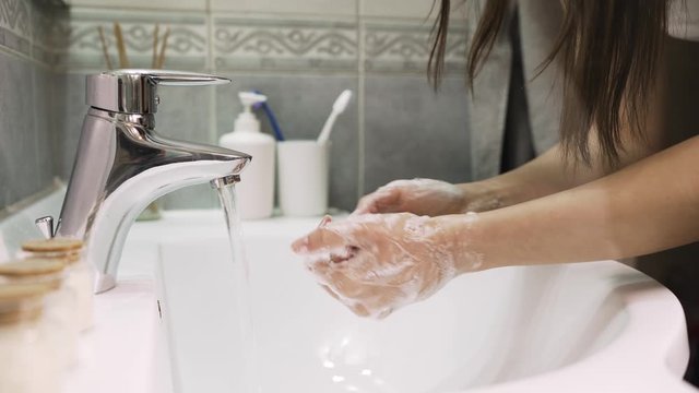 Woman washing hands with soap and water in clean bathroom.Decontamination protocol,hand hygiene routine.Cleaning hands regularly.Infectious disease prevention/protection.Handwashing disinfection