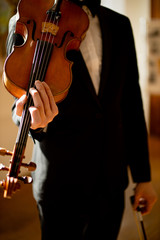 cropped elegant talented professional violinist performing classical music, handsome guy in formal suit holding violin. classical music and instruments concept