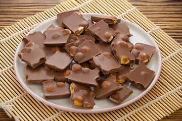 Delicious milk chocolate with hazelnuts on wooden background