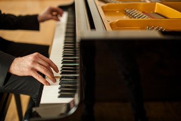 cropped unrecognizable male in suit playing piano on a stage. handsome guy gracefully play piano, practice before performance