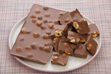 Delicious milk chocolate with hazelnuts on wooden background