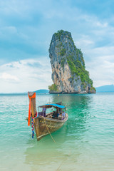 thailand islands with rocks and vegetation at the edge of the blue sea clean and blue sky and longtail boat beautiful sunny day in southeast asia
