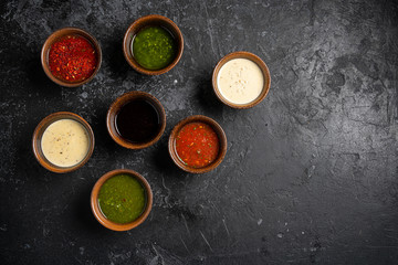 Set of different sauces with names on wooden background.