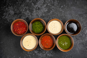 Set of different sauces with names on wooden background.