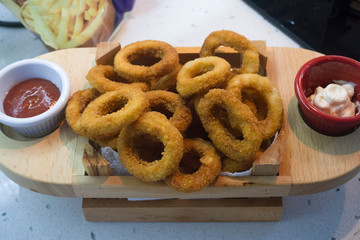 Onion rings in a wooden bowl or pot. Fast food, gaining weight concept.