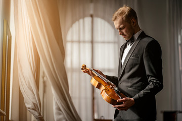 young caucasian male violinist hold violin in hands, professional musician going to play on violin,...
