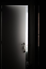 Silver handle with decoration on a white door with light coming from the bedroom