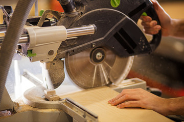 cropped photo of carpenter male using circular saw for cutting wooden boards, woodworker at his work place. close-up photo