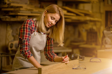 Fototapeta premium portrait of professional woodworker making marks on wooden piece, woman make handmade furniture in workshop, enjoy working alone