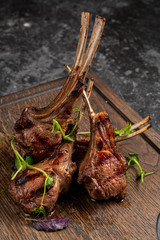 Grilled lamb ribs on cutting board. Hot rack of lamb with spices and condiments. Top view on wooden table © sutulastock