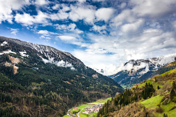 Fototapeta na wymiar Aerial view of valley with green slopes of the mountains of Italy, Trentino, The trees tumbled down by a wind, huge clouds over a valley, green meadows, Dolomites on background, cloudy weather