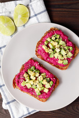 Variation of healthy rye toasts with avocado and beetroot on a plate. Delicious snacks, avocado sandwiches. Food composition, tasty italian meal. Close up, top view