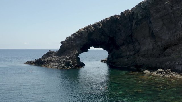 The sea of ​​Pantelleria with its jagged and volcanic coast. Turquoise colored sea. Dammusi, typical houses of Pantelleria.