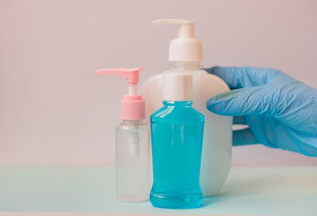 girl holds in her hands bottles with an antiseptic with liquid soap for cleanliness against bacteria in blue rubber gloves