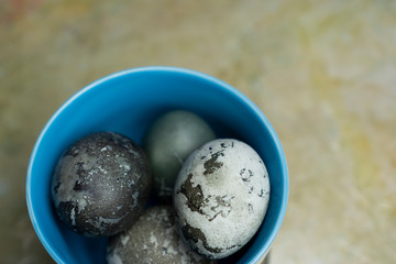 Blue plate bowl with marble pastel coloured Easter eggs table top view close-up with space