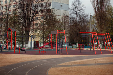 Obraz premium Kharkov, Ukraine, 18.04.2020: Closed on quarantine by covid-19 kids playground with tied of white and red boundary tape in carantin time with warning sign, medium shot 
