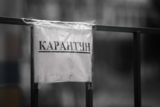 Kharkov, Ukraine, 18.04.2020:
Warning sign about quarantine by covid-19 on the iron fence of the school, black and white, head shot 