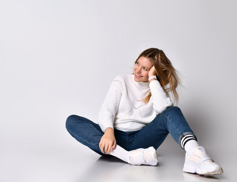 Blonde teen girl in jeans, sweater, socks and sneakers. She smiling, posing  sitting on floor, isolated on white. Close up Stock Photo | Adobe Stock
