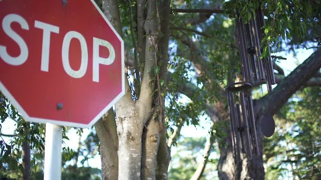 Stop sign next to wind chimes, swaying in the breeze