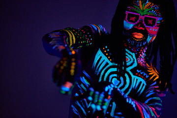 UV body art concept. young cyber raver dance, fluorescent make-up, colorful prints on shirtless skin
