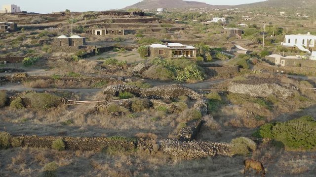 The sea of ​​Pantelleria with its jagged and volcanic coast. Turquoise colored sea. Dammusi, typical houses of Pantelleria.
