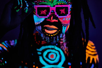 portrait of young unrecognizable man in sunglases with fluorescent prints on skin, cool handsome fashionable guy posing at camera