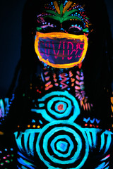 Fototapeta na wymiar portrait of african male posing with COVID-19 inscription on mask, fluorescent prints glows on neon lights, fight with coronavirus
