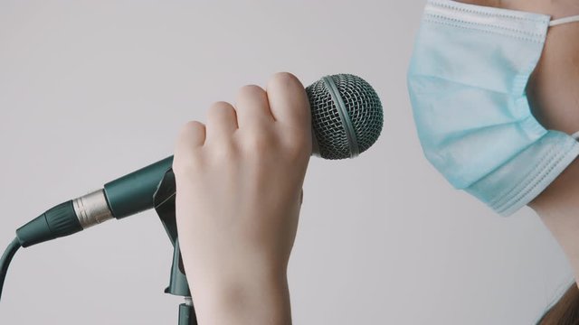 Young singer singing in the microphone fith face mask in home studio. Remote work, self issolation and prevention of coronavirus spread