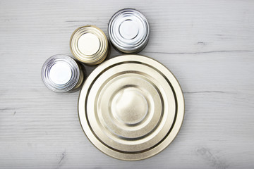 Various closed tin cans with food preserves on a light background. Canned food concept. Food donations. Copy space.