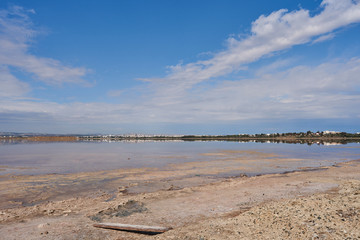 Beautiful panoramic view from the shore of the salty lake Larnaca with blue sky and small clouds, reflections in the water, Larnaca, island Cyprus, deserted landscape