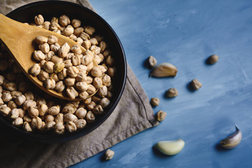 Raw chickpeas in a bowl and wood spoon.