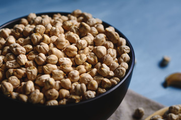 Raw chickpeas in a bowl and wood spoon.