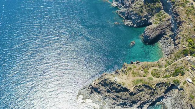 The sea of ​​Pantelleria with its jagged and volcanic coast. Turquoise colored sea. Dammusi, typical houses of Pantelleria.