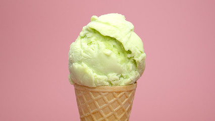 Flavoured lime sherbet ice cream in waffle cone on pink background, Front view Food concept.