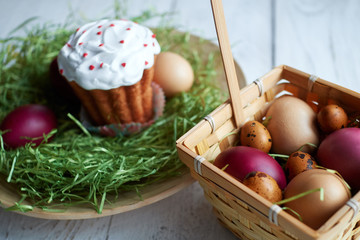 Easter basket and Easter cake on a light wooden background