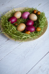 Easter colored eggs in a plate on a light wooden background