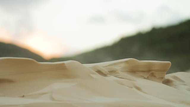 Wind blowing sand and forming geometrical shapes in a dune. Mountains in the background. Telephoto lens shot (500mm) Joaquina beach. Florian&oacute;polis, Santa Catarina / Brazil