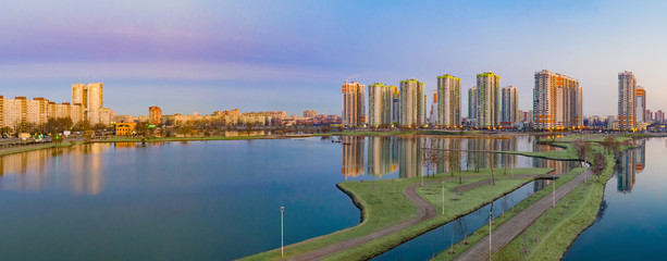 Fototapeta na wymiar City panorama in the early morning. Residential building next to the ponds. Walking area with lakes next to the new residential complex. Modern housing construction. Apartments in new buildings.