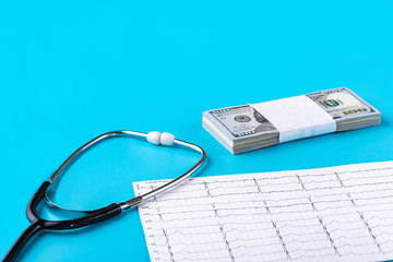 Stethoscope, cardiogram, US banknotes on a blue background close-up. Copy-space. Concept of the Economics USA of medicine.