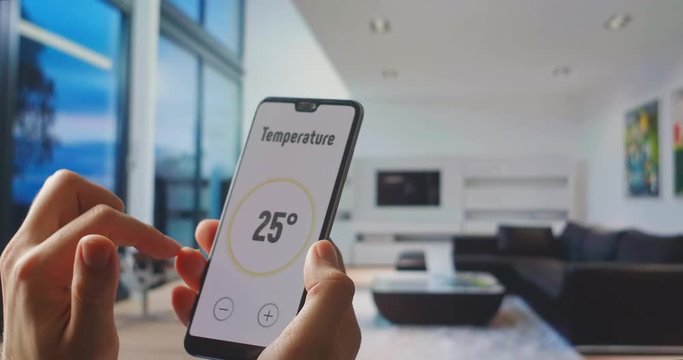 Home automation and remote control. Internet things and modern smart technology. Young Handsome Man Gives Command to a Smart Home Application on His Smartphone. Using smart home app on digital device