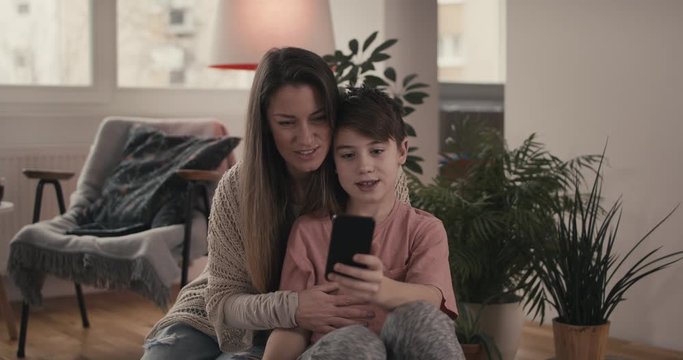 Mother and son have a video call chat virtual connection on a smartphone together with dad stay at home