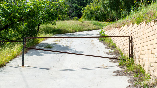 a metal gate blocking an abandoned road heading up a lush wooded hillside