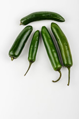 Five spicy jalapeño chili peppers lay on a white table.