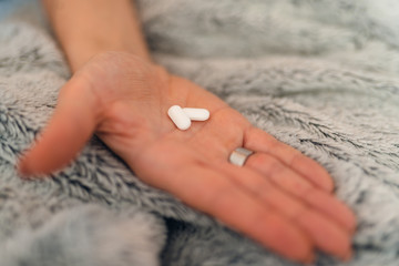 Close up of pills in the hand of a sick caucasian woman