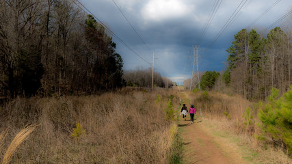 Women walking along path next to power lines with storm clouds in the background