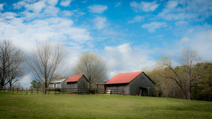 Fototapeta na wymiar Small barns in a field with cloudy blue sky in the background