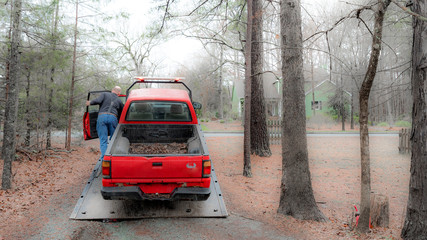 Obraz na płótnie Canvas Red pickup truck being loaded on red tilt bed tow truck to be hauled away