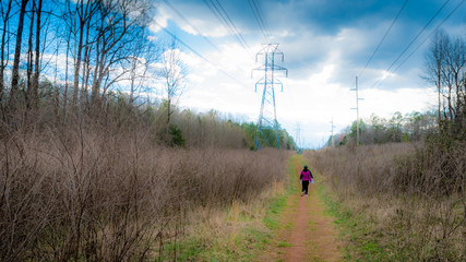 Women walking along path next to power lines with storm clouds in the background