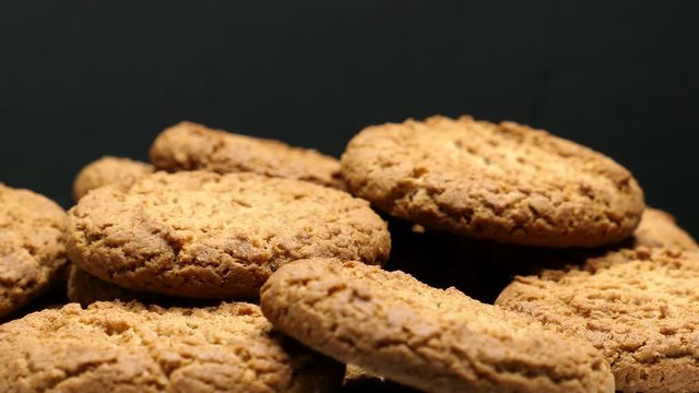 Rotating Close Up Of Fresh Brown Oatmeal Cookies On A White Plate On A Black Background.