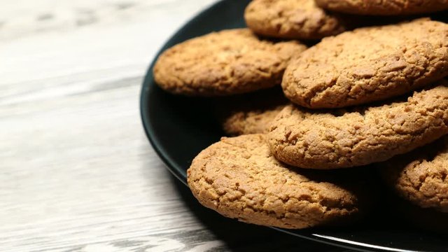 Fresh Brown Oatmeal Cookies On A Black Plate On A Gray Wooden Background Panning Slider Shot, Close-up..
